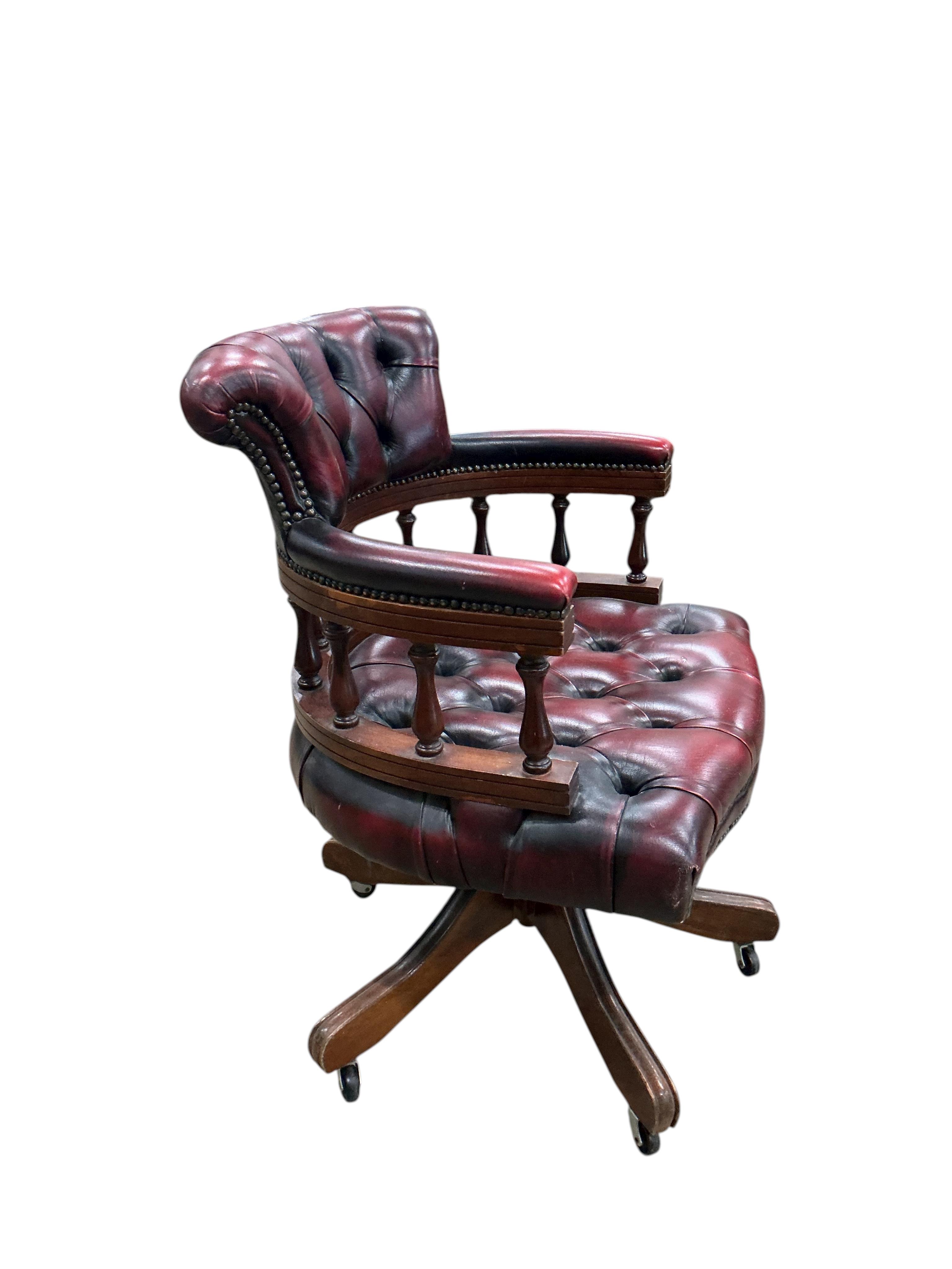 A late 20th century revolving desk chair upholstered in buttoned claret leather, width 62cm, depth 56cm, height 82cm